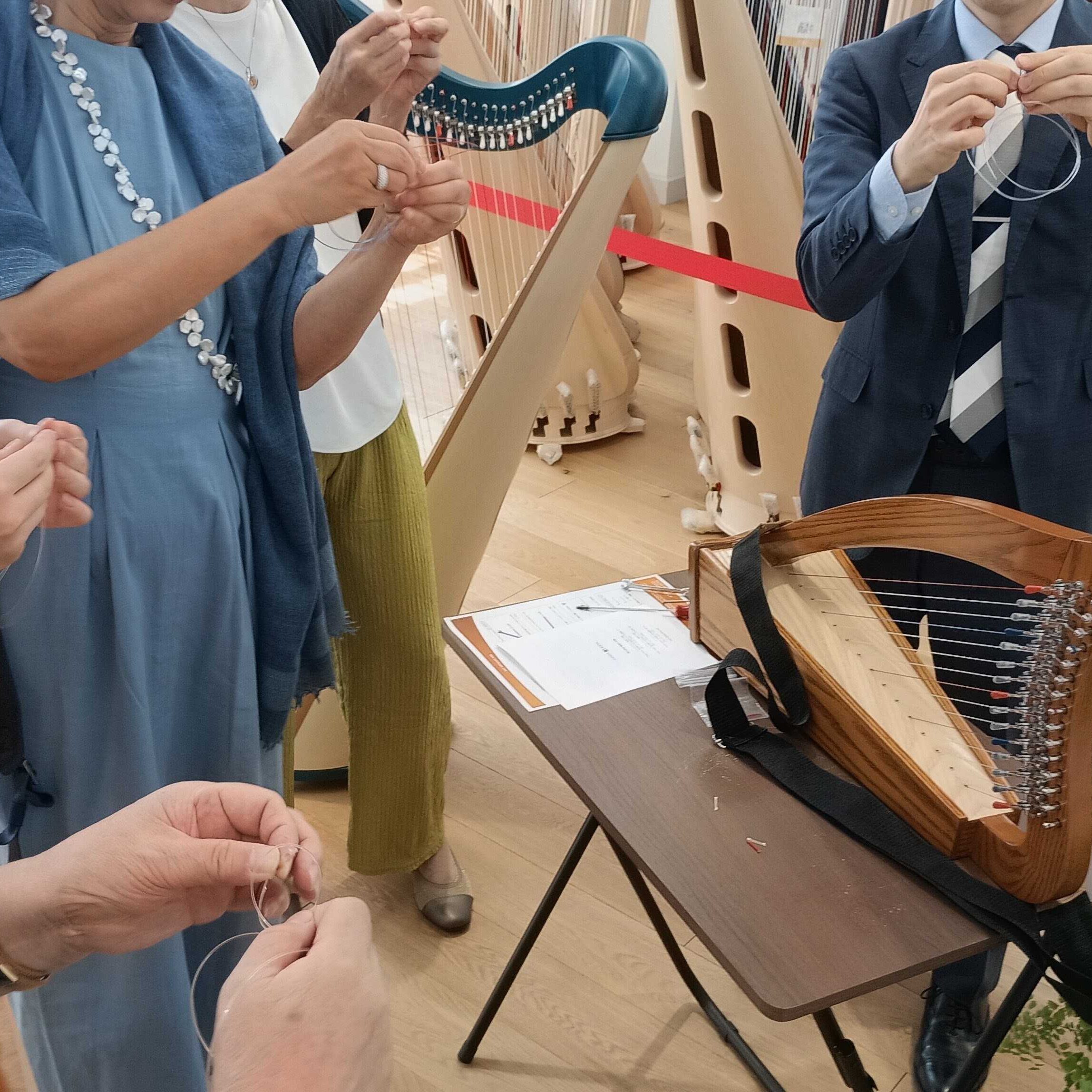 ハープの弦交換を体験する来場者