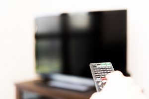 テレビにリモコンを向ける手（映画鑑賞のイメージ）