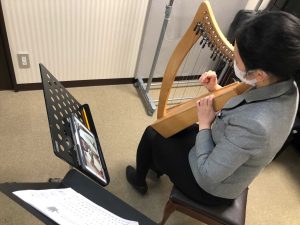 タブレットを見ながらベイビーハープを弾く様子
