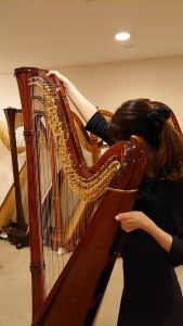 上担当が左手をサウンドホールに、右手をネックに添えて楽器を傾ける様子