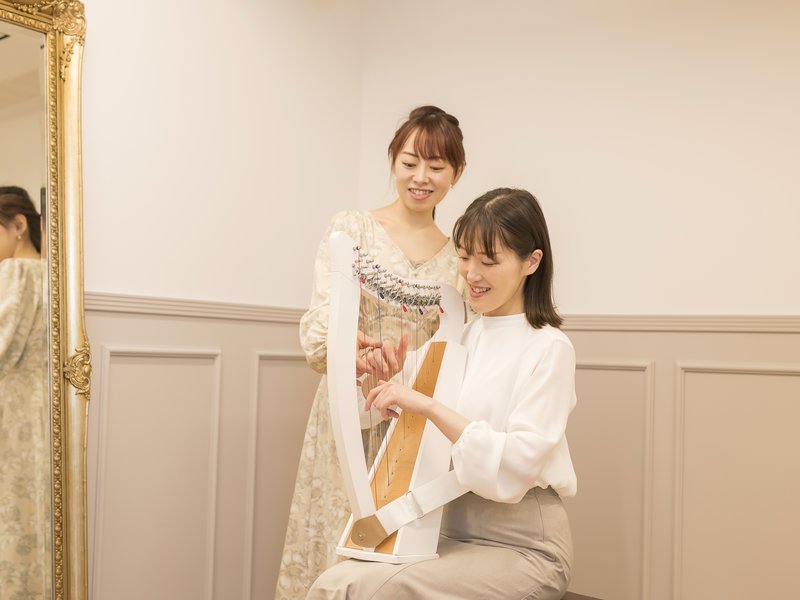 ひざにのせたクリスハープの弦に触れて音を出す様子
