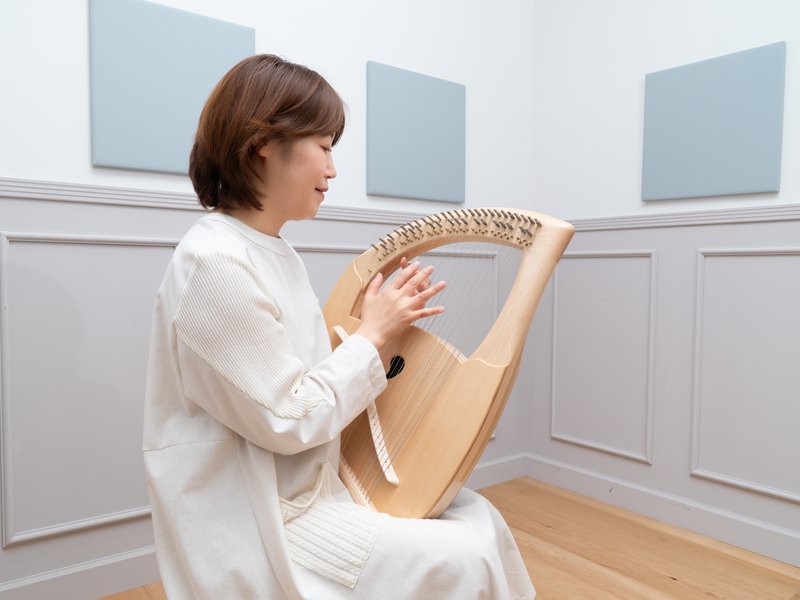 ひざにのせたライアーを、両手で弦を撫でるようにして奏でる様子