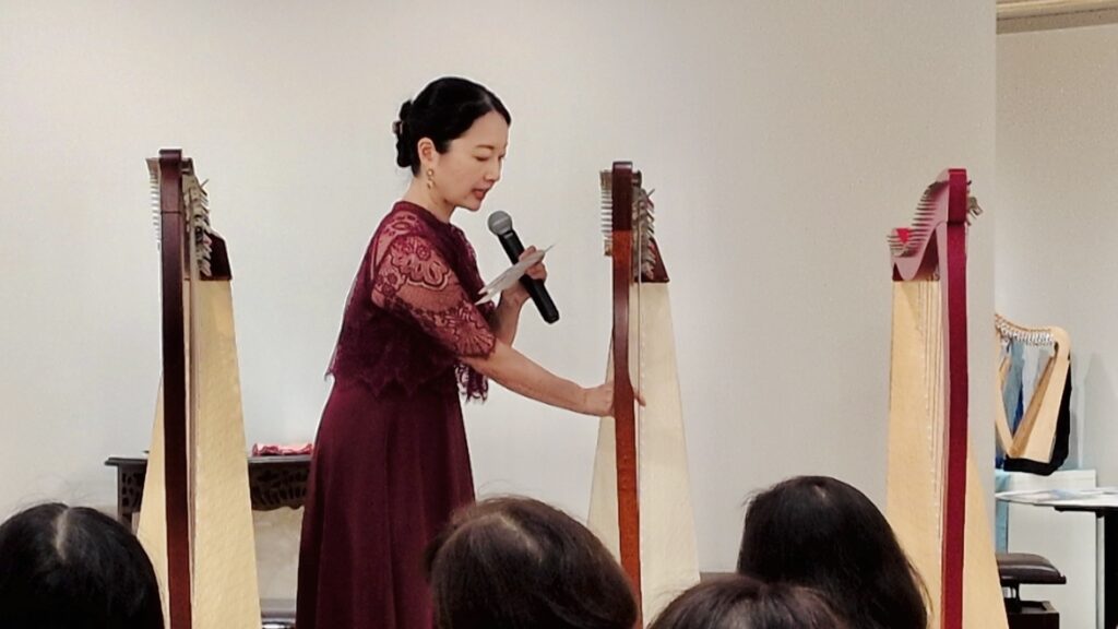 4台のレバーハープを前にマイクで解説する高山聖子先生