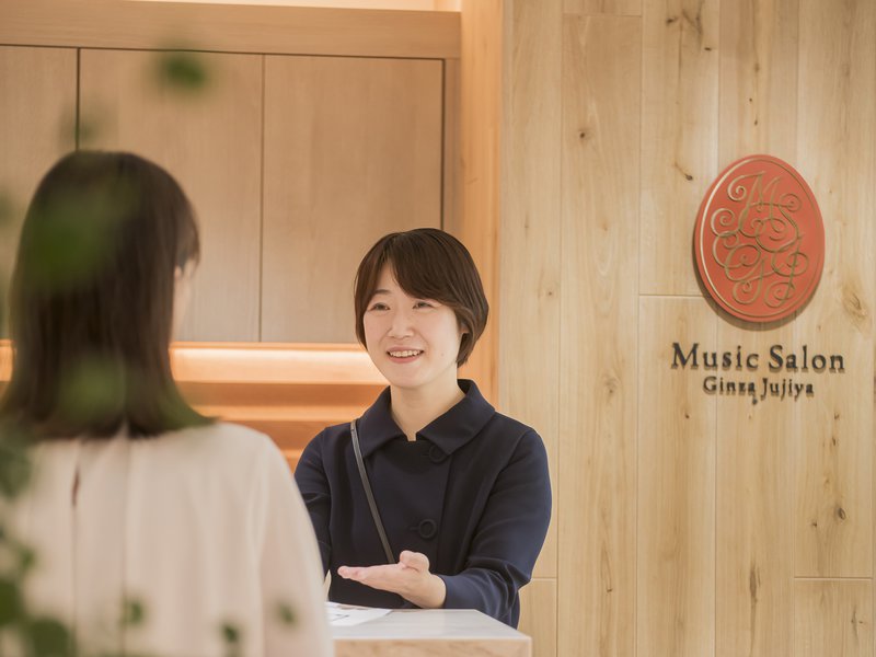 ミュージックサロン銀座十字屋の受付で、スタッフがお客様にご案内する様子