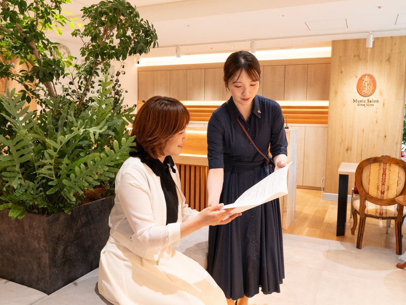 ラウンジで資料を見せながら説明する銀座十字屋のスタッフと、椅子に座って聞くお客様